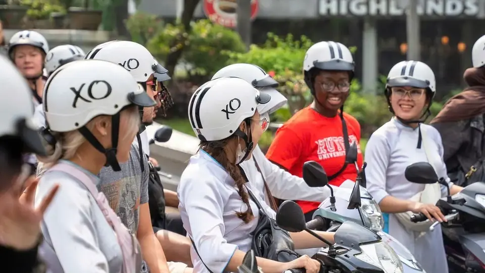 XO Tours guides in áo dài and guests in XO helmets lined up on motorbikes in Ho Chi Minh City