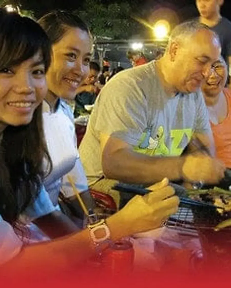 Guests and guides eating together at a Saigon street food stall after dark